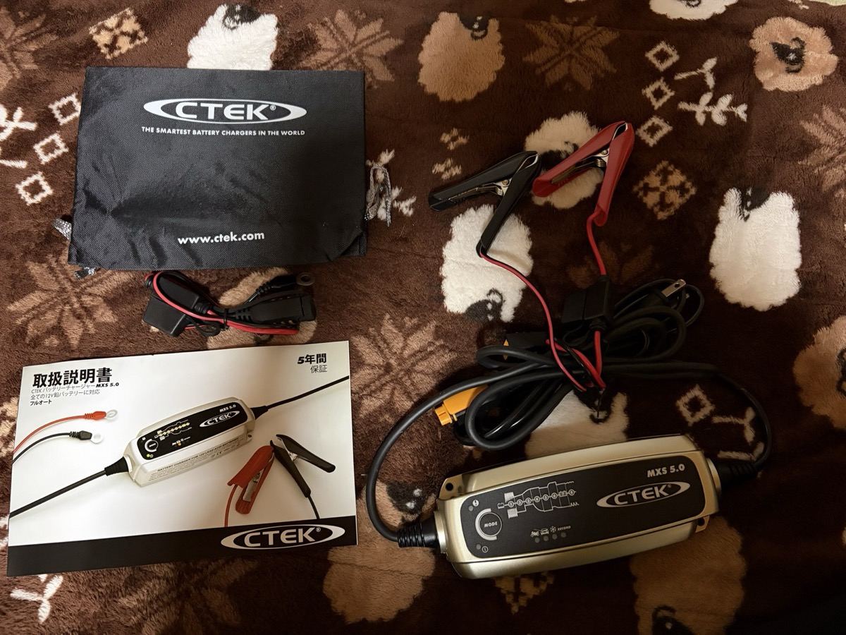 CTEK MXS 5.0の本体と、クリップ、アイレット、取扱説明書、収納袋