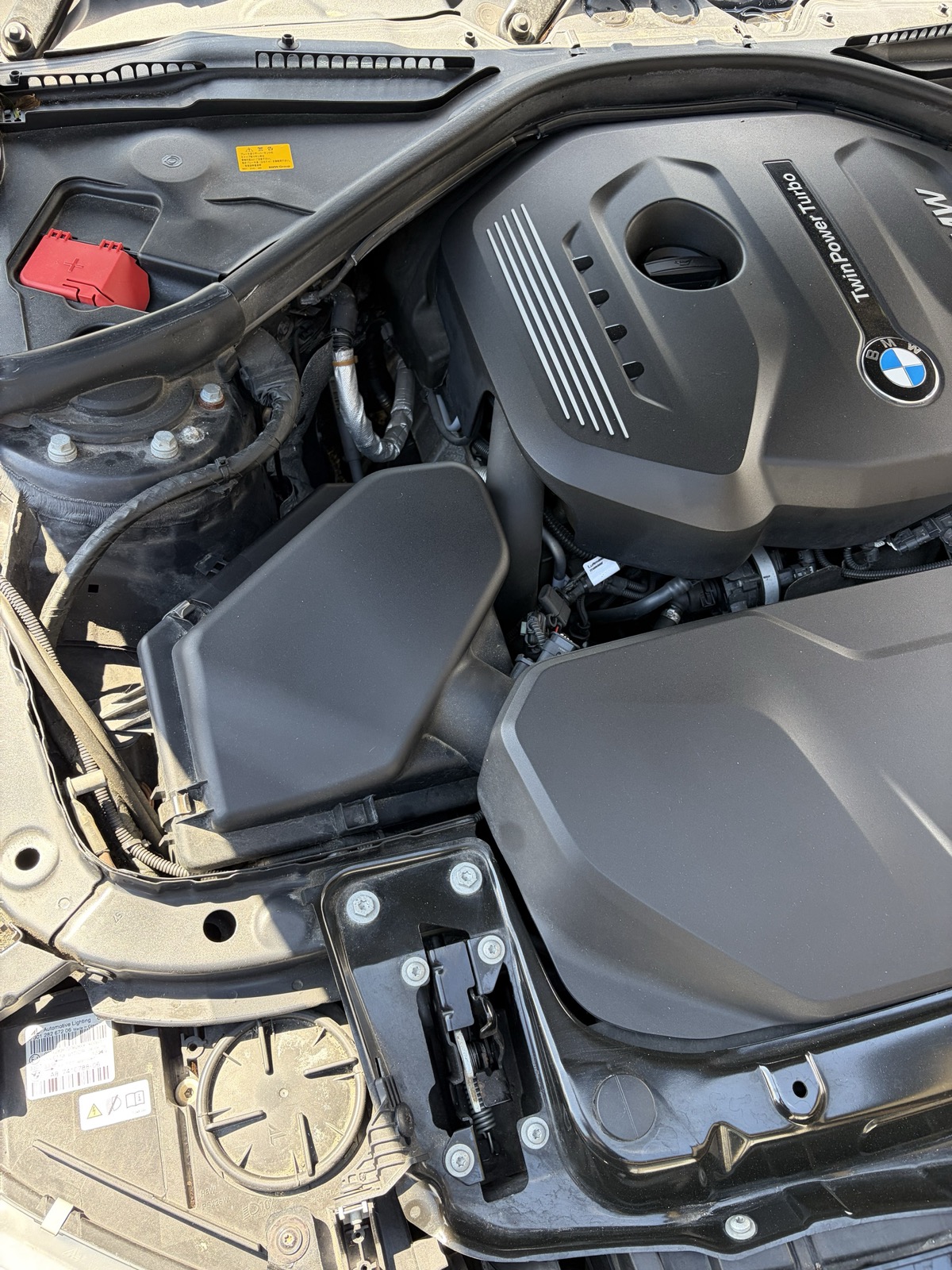 BMW 420iのエンジンルーム。奥の端に赤いカバーのジャンプスタート用プラス端子がある
